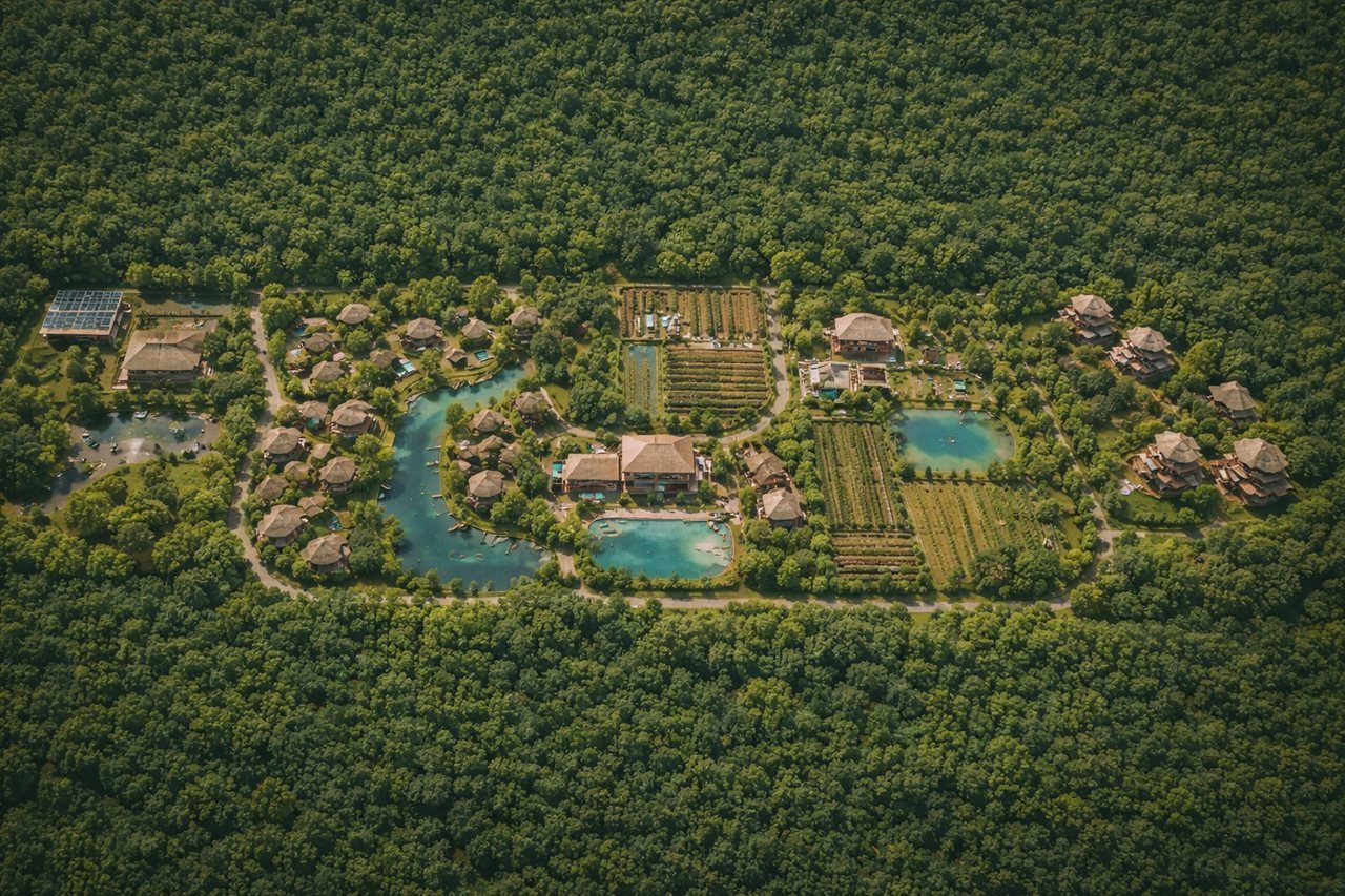 Vista aérea de un resort de bajo impacto en medio de la selva, con cabañas, cenotes y huertos.